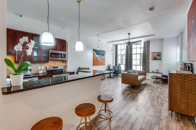 1122 Jackson St Unit 220, Dallas, TX 75202 - kitchen featuring stainless steel appliances, a kitchen bar, wood finished floors, glass insert cabinets, and ceiling fan