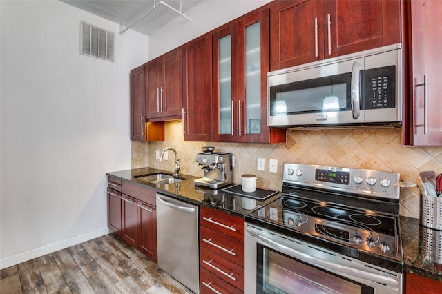 1122 Jackson St Unit 220, Dallas, TX 75202 - kitchen featuring appliances with stainless steel finishes, a sink, dark brown cabinets, wood finished floors, and dark stone counters