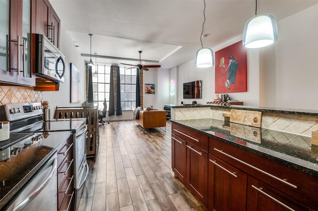 1122 Jackson St Unit 220, Dallas, TX 75202 - kitchen featuring stainless steel appliances, tasteful backsplash, wood finished floors, decorative light fixtures, and dark stone countertops