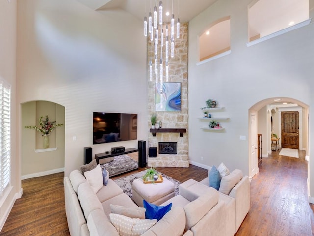 2040 Grassland Dr, Allen, TX 75013 - living room featuring a towering ceiling, arched walkways, baseboards, wood finished floors, and a stone fireplace