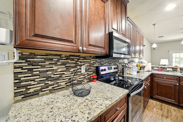 2901 18th St, Fort Worth, TX 76106 - kitchen featuring stainless steel appliances, decorative backsplash, light stone counters, decorative light fixtures, and light wood-style flooring