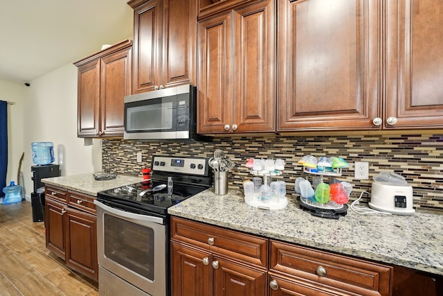2901 18th St, Fort Worth, TX 76106 - kitchen with stainless steel appliances, backsplash, light wood finished floors, light stone countertops, and brown cabinets