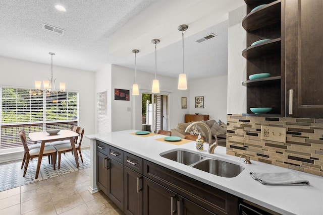 2506 Wedglea Dr Unit 907, Dallas, TX 75211 - kitchen with open shelves, dark brown cabinets, healthy amount of natural light, a sink, and a textured ceiling