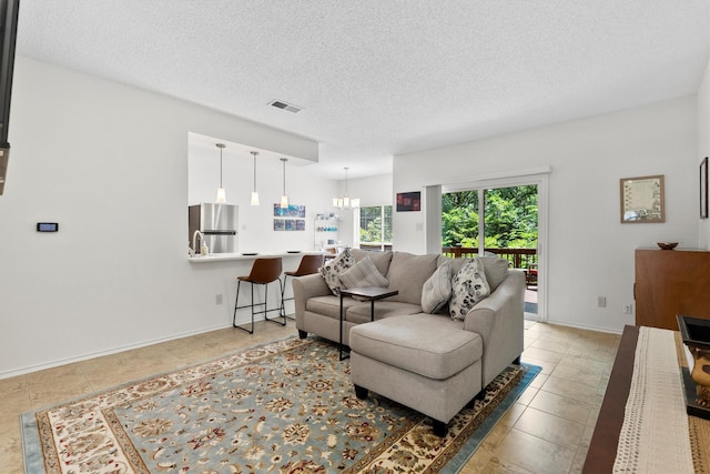 2506 Wedglea Dr Unit 907, Dallas, TX 75211 - living room with a chandelier, a textured ceiling, light tile patterned floors, and baseboards