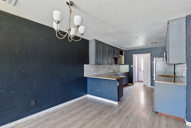 5608 Humbert Ave, Fort Worth, TX 76107 - kitchen featuring baseboards, light wood-type flooring, tasteful backsplash, a chandelier, and a textured ceiling