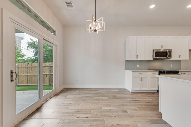 137 Willow Ln, Roanoke, TX 76262 - kitchen with stainless steel microwave, white cabinets, light wood-style flooring, light countertops, and backsplash