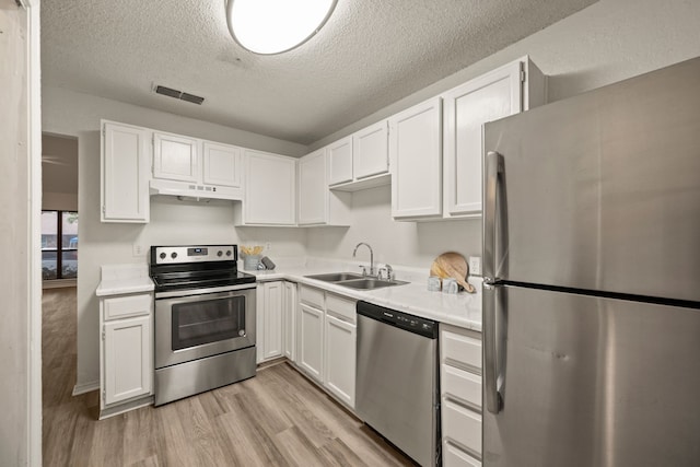 2911 Post Oak Dr, Euless, TX 76039 - kitchen with appliances with stainless steel finishes, a sink, under cabinet range hood, white cabinets, and a textured ceiling
