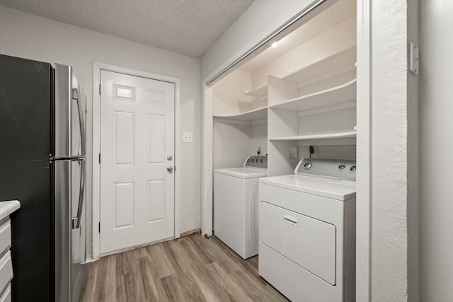 2911 Post Oak Dr, Euless, TX 76039 - laundry area featuring light wood-type flooring, washing machine and clothes dryer, and a textured ceiling