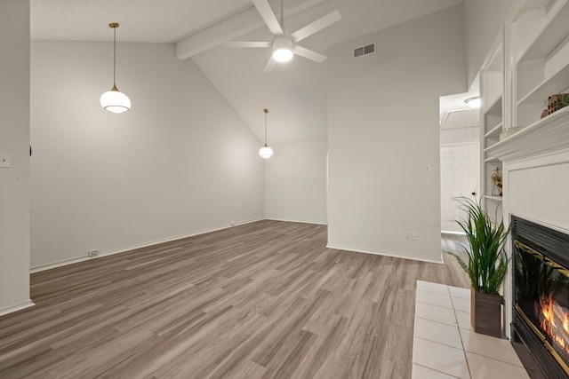 2911 Post Oak Dr, Euless, TX 76039 - unfurnished living room featuring beamed ceiling, a glass covered fireplace, ceiling fan, light wood finished floors, and high vaulted ceiling