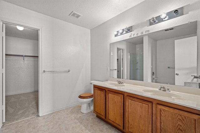 16616 Jasmine Springs Dr, Fort Worth, TX 76247 - bathroom featuring double vanity, a stall shower, a walk in closet, toilet, and baseboards
