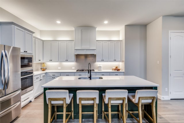 1421 Benavites Dr, Little Elm, TX 75068 - kitchen with appliances with stainless steel finishes, light wood-style floors, a breakfast bar, tasteful backsplash, and recessed lighting