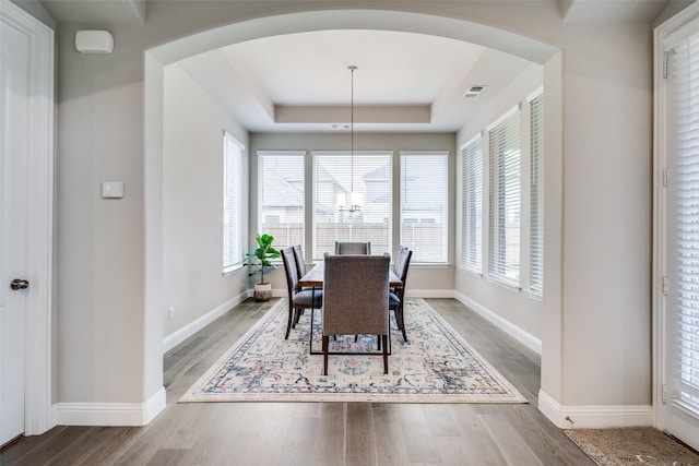 1421 Benavites Dr, Little Elm, TX 75068 - dining space featuring arched walkways, wood finished floors, a raised ceiling, and baseboards