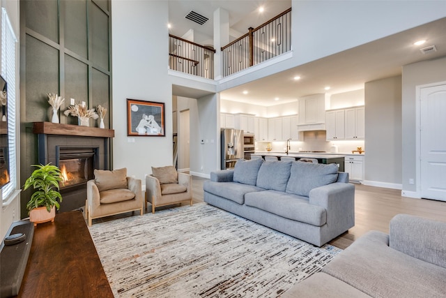 1421 Benavites Dr, Little Elm, TX 75068 - living room with baseboards, a towering ceiling, light wood finished floors, a large fireplace, and recessed lighting