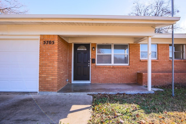 5705 Wheaton Dr, Fort Worth, TX 76133 - view of exterior entry with brick siding, a garage, and concrete driveway