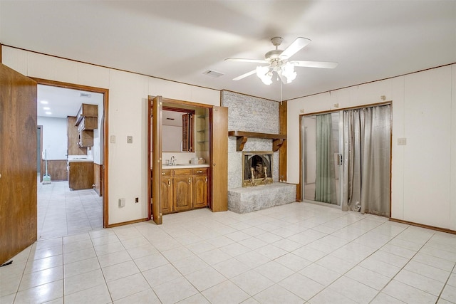 502 Roaring Springs Dr, Joshua, TX 76058 - unfurnished living room featuring a ceiling fan, a sink, a stone fireplace, light tile patterned floors, and wooden walls