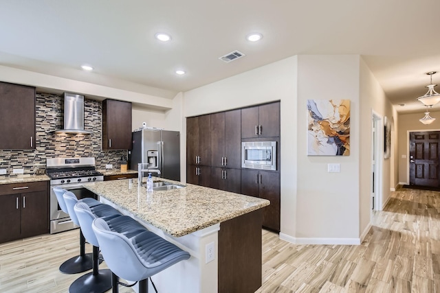 3446 Kirby Ln, Forney, TX 75126 - kitchen featuring appliances with stainless steel finishes, wall chimney exhaust hood, a sink, light wood-style floors, and a breakfast bar