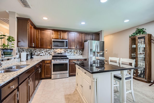 8745 Twin Pines Ln, Frisco, TX 75036 - kitchen featuring appliances with stainless steel finishes, a breakfast bar area, decorative backsplash, light stone countertops, and recessed lighting