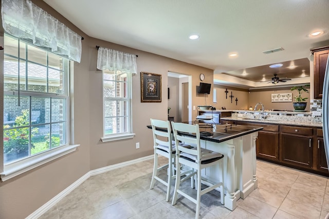 8745 Twin Pines Ln, Frisco, TX 75036 - kitchen with a sink, a kitchen bar, dark brown cabinetry, baseboards, and recessed lighting
