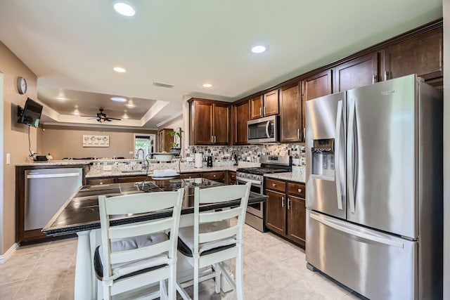 8745 Twin Pines Ln, Frisco, TX 75036 - kitchen featuring stainless steel appliances, dark brown cabinets, tasteful backsplash, a ceiling fan, and a sink