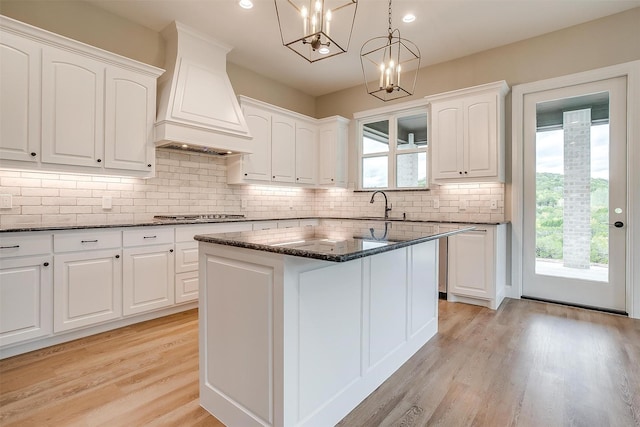8732 Fullerton Dr, Cleburne, TX 76033 - kitchen with dark stone countertops, light wood finished floors, custom exhaust hood, a sink, and recessed lighting