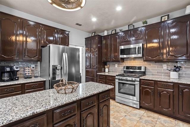 7705 Marble Canyon Ct, Fort Worth, TX 76137 - kitchen with appliances with stainless steel finishes, decorative backsplash, dark brown cabinetry, light stone countertops, and recessed lighting