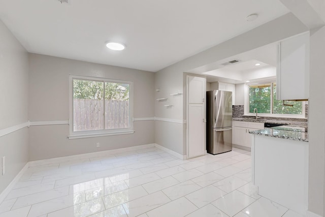 1723 Overbrook Dr, Arlington, TX 76014 - kitchen with freestanding refrigerator, light marble finish floors, white cabinets, baseboards, and light stone counters