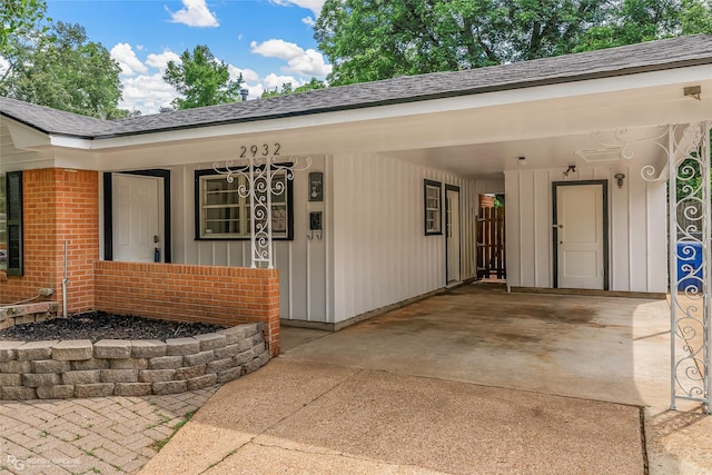2932 W Cavett Dr, Shreveport, LA 71104 - property entrance featuring driveway, an attached carport, a shingled roof, brick siding, and a porch
