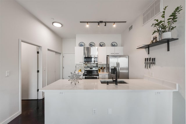 3025 Bryan St Unit 1F, Dallas, TX 75204 - kitchen featuring appliances with stainless steel finishes, open shelves, a peninsula, a sink, and track lighting
