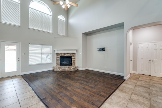 13274 Bayfield Dr, Frisco, TX 75033 - unfurnished living room with a ceiling fan, a towering ceiling, plenty of natural light, a stone fireplace, and tile patterned flooring