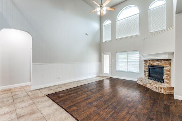 13274 Bayfield Dr, Frisco, TX 75033 - unfurnished living room with a towering ceiling, a ceiling fan, a stone fireplace, baseboards, and wood finished floors