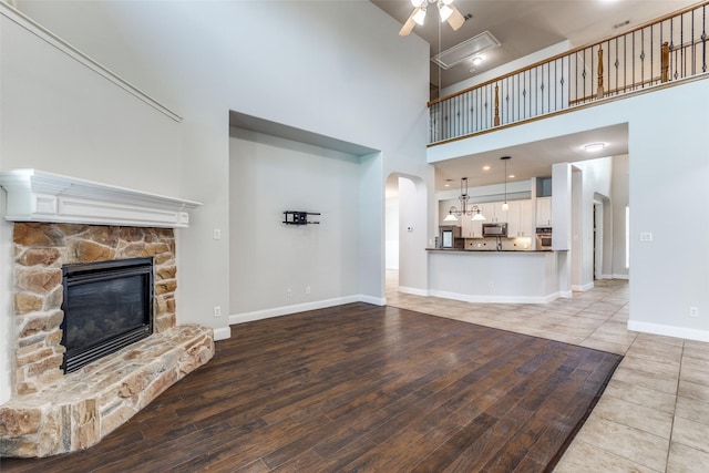 13274 Bayfield Dr, Frisco, TX 75033 - unfurnished living room with ceiling fan, a high ceiling, a stone fireplace, arched walkways, and baseboards