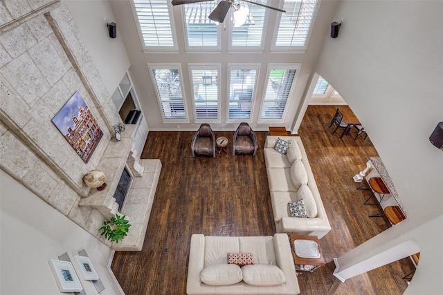 15630 Stonebridge Dr, Frisco, TX 75035 - living room featuring a fireplace with raised hearth, a high ceiling, ceiling fan, wood finished floors, and baseboards