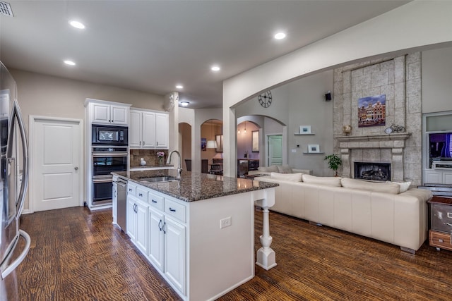 15630 Stonebridge Dr, Frisco, TX 75035 - kitchen with appliances with stainless steel finishes, a sink, arched walkways, open floor plan, and dark stone counters