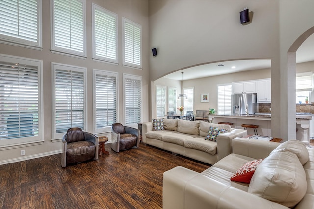 15630 Stonebridge Dr, Frisco, TX 75035 - living area with arched walkways, a towering ceiling, plenty of natural light, dark wood finished floors, and baseboards