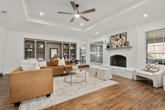 2005 Westshore Dr, Garland, TX 75043 - living area featuring wood finished floors, a ceiling fan, a brick fireplace, a tray ceiling, and built in features