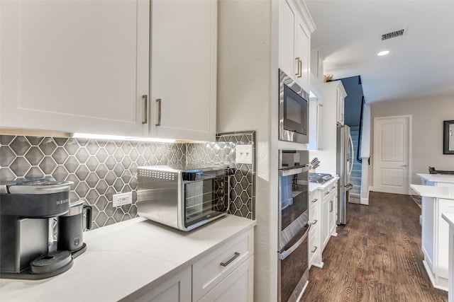 2758 Sharlis Dr, Frisco, TX 75036 - kitchen with stainless steel appliances, white cabinets, decorative backsplash, dark wood-style floors, and light stone countertops