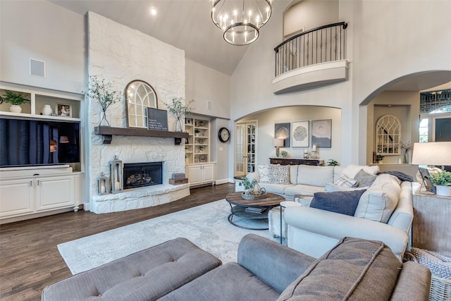 2758 Sharlis Dr, Frisco, TX 75036 - living area featuring arched walkways, dark wood-type flooring, high vaulted ceiling, a stone fireplace, and a chandelier