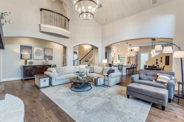 2758 Sharlis Dr, Frisco, TX 75036 - living room with a chandelier, arched walkways, dark wood-style floors, stairs, and a towering ceiling