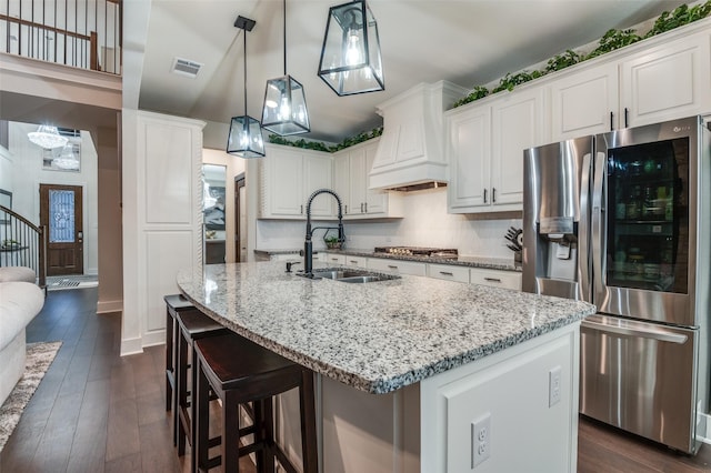 1405 Thunder Dove Dr, Mansfield, TX 76084 - kitchen with stainless steel fridge, a sink, custom range hood, light stone counters, and dark wood-type flooring