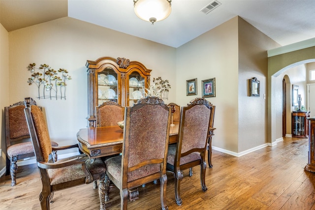 140 Daisey Ln, Justin, TX 76247 - dining room featuring arched walkways, light wood finished floors, lofted ceiling, and baseboards