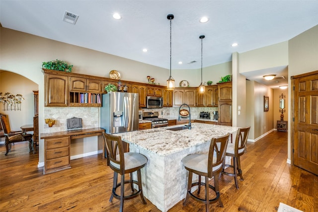 140 Daisey Ln, Justin, TX 76247 - kitchen featuring stainless steel appliances, a sink, backsplash, hardwood / wood-style flooring, and a center island with sink