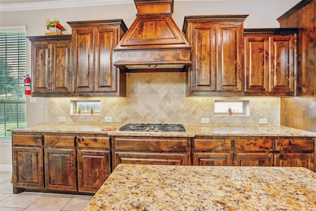 1001 Vineyard Dr, Euless, TX 76039 - kitchen with custom range hood, stainless steel gas stovetop, light stone countertops, light tile patterned floors, and ornamental molding