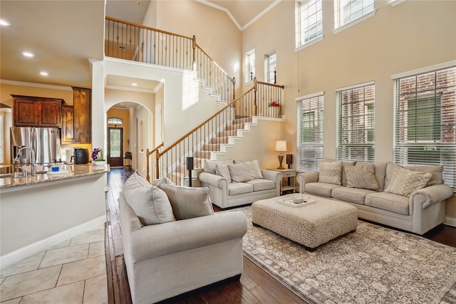 1001 Vineyard Dr, Euless, TX 76039 - living area with arched walkways, ornamental molding, stairs, a towering ceiling, and baseboards