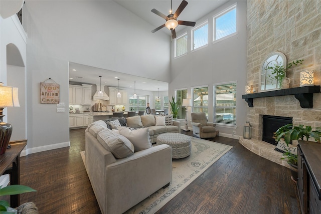 760 Ascot Ct, Prosper, TX 75078 - living area featuring a towering ceiling, a ceiling fan, a stone fireplace, dark wood-style flooring, and baseboards
