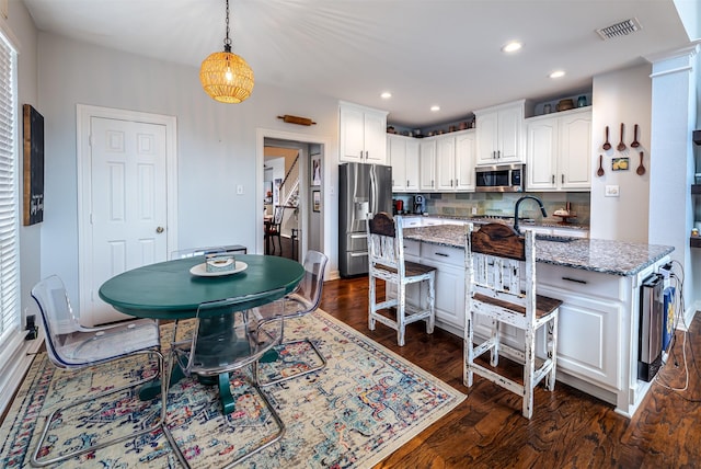 1015 W Bluff St, Fort Worth, TX 76102 - kitchen with appliances with stainless steel finishes, a kitchen bar, white cabinetry, light stone countertops, and dark wood finished floors