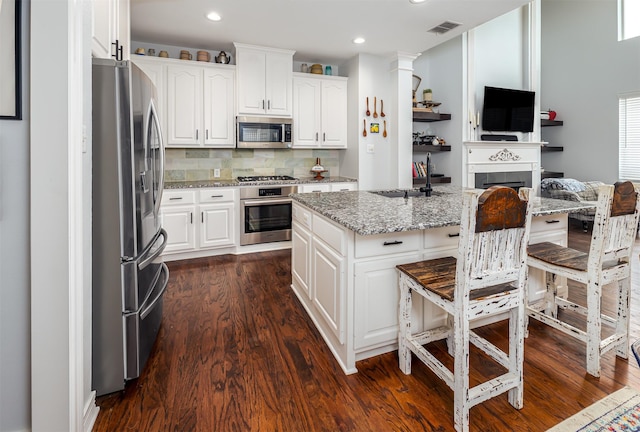 1015 W Bluff St, Fort Worth, TX 76102 - kitchen with appliances with stainless steel finishes, a sink, a kitchen bar, dark wood-type flooring, and a kitchen island