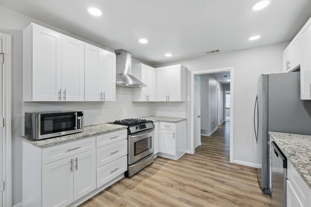 4900 Vega Ct E, Fort Worth, TX 76133 - kitchen featuring appliances with stainless steel finishes, wall chimney range hood, tasteful backsplash, baseboards, and light wood-style flooring