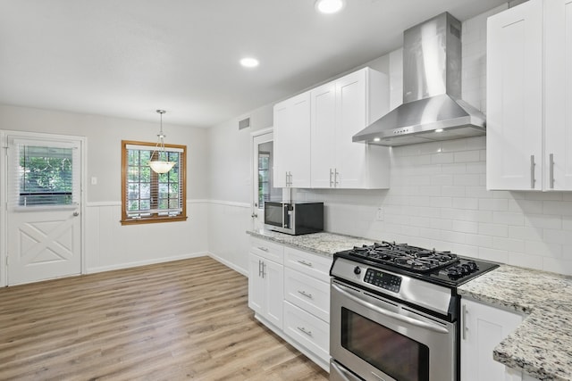 4900 Vega Ct E, Fort Worth, TX 76133 - kitchen featuring appliances with stainless steel finishes, wall chimney range hood, white cabinets, light wood-type flooring, and wainscoting