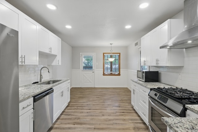4900 Vega Ct E, Fort Worth, TX 76133 - kitchen with appliances with stainless steel finishes, wall chimney exhaust hood, a sink, white cabinetry, and a wainscoted wall