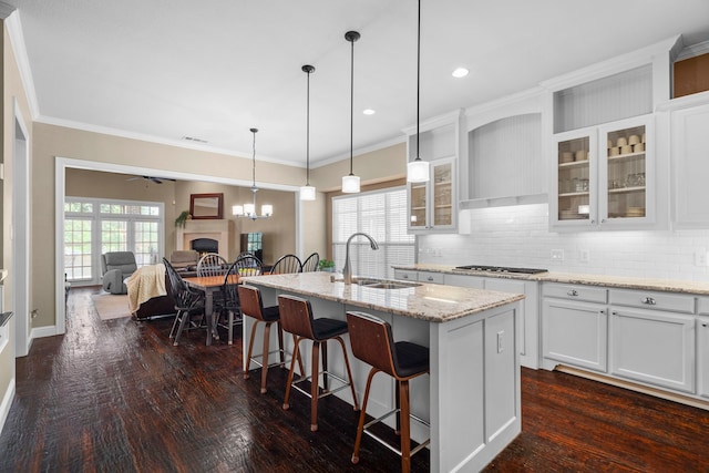8920 Cypress Creek Rd, Lantana, TX 76226 - kitchen featuring a sink, stainless steel gas cooktop, a fireplace, a kitchen breakfast bar, and decorative backsplash